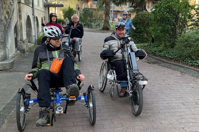 Einige Personen fahren mit ihren Rollstühlen Rad. Die Stimmung ist locker und gelöst, es wird viel gelacht.