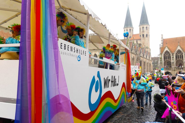 Der Schoduvel-Wagen der Lebenshilfe Braunschweig: Bunt geschmückt, mit vielen Menschen drauf und drumherum.