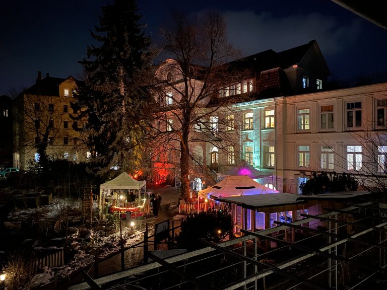 Blick vom Balkon in den Ludwigsgarten. Es ist dunkel und der Garten ist beleuchtet.